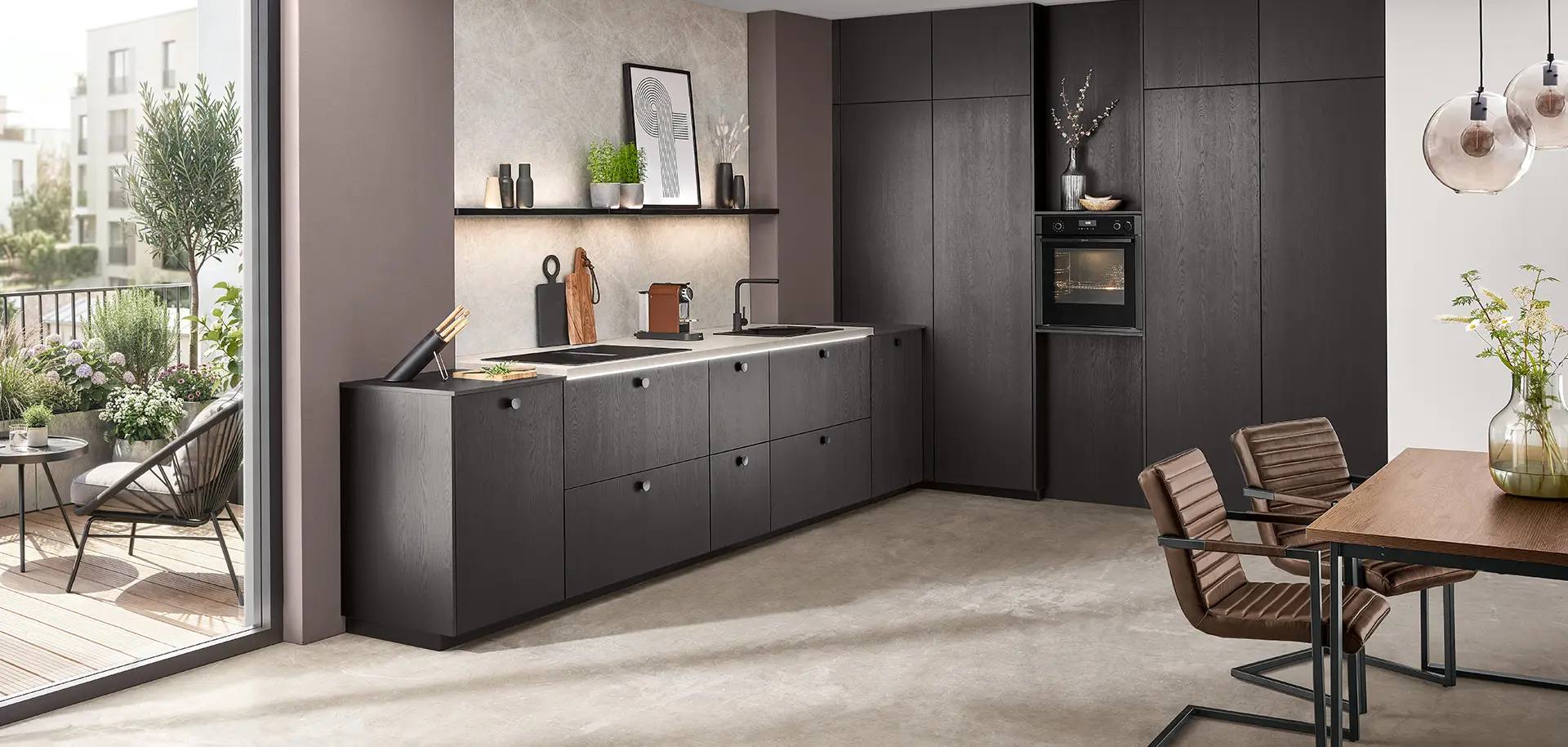 Küche mit Fronten in Eiche Nero, heller Arbeitsplatte und Essplatz mit Holztisch