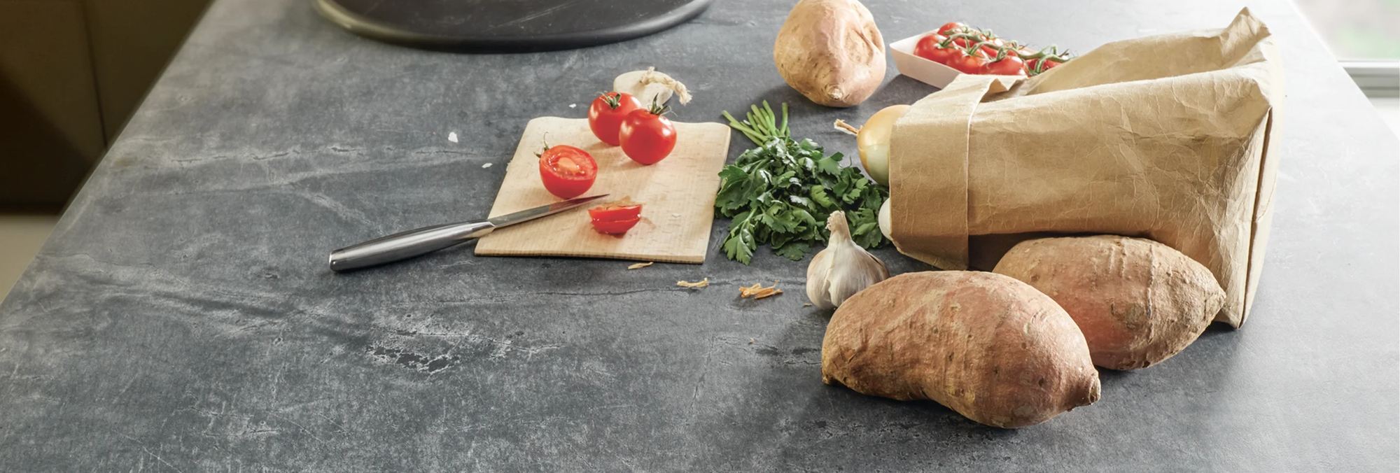 Schüller Arbeitsplatte in grauer Steinoptik mit Schneidebrett, Tomaten und Brot